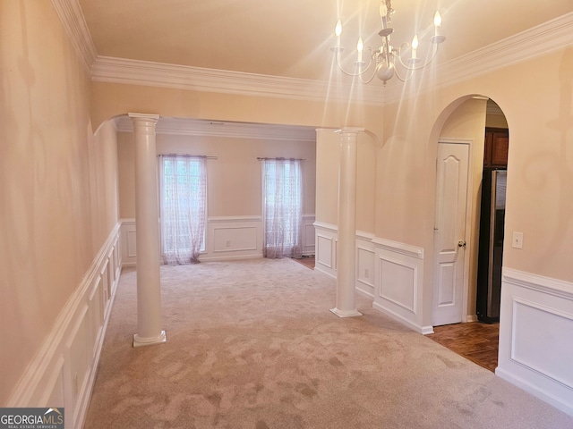 hall with crown molding, a notable chandelier, carpet floors, and decorative columns