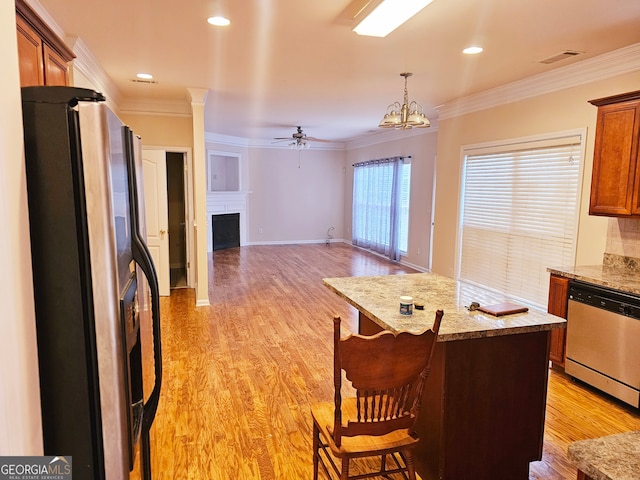 kitchen featuring appliances with stainless steel finishes, ceiling fan with notable chandelier, hanging light fixtures, ornamental molding, and light hardwood / wood-style flooring