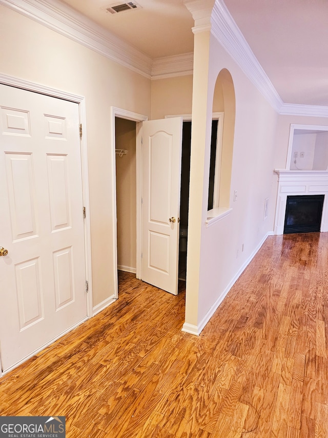 unfurnished living room with ornamental molding and light hardwood / wood-style floors