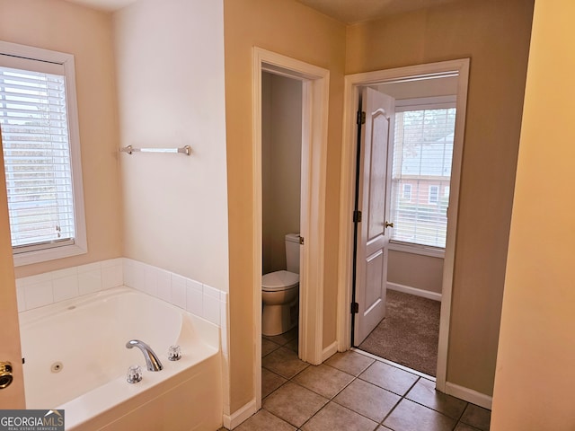 bathroom with tile patterned floors, a tub, toilet, and plenty of natural light