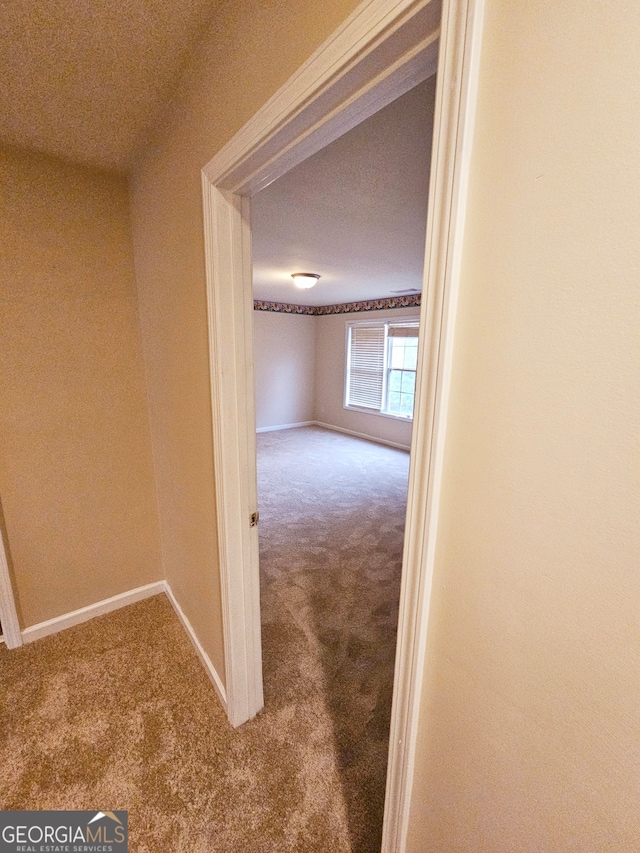 hall with a textured ceiling and carpet flooring