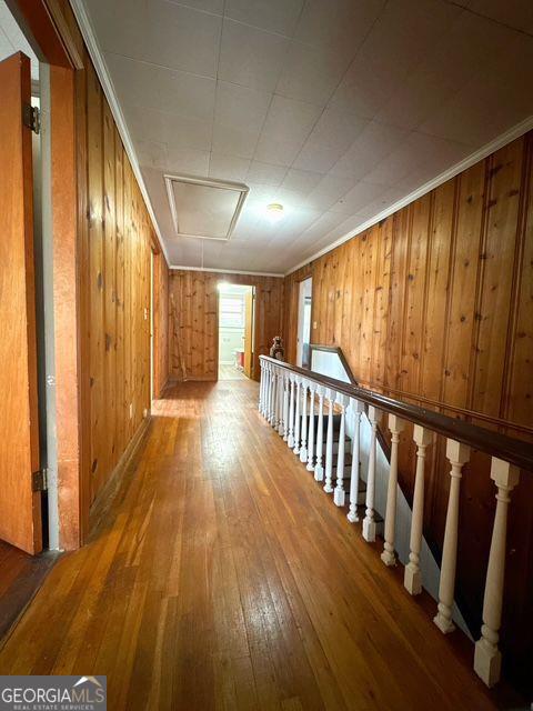 hall featuring hardwood / wood-style flooring, wood walls, and crown molding