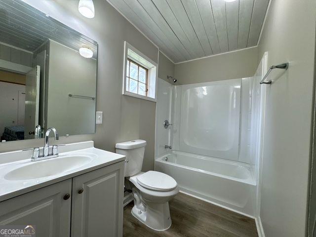 full bathroom featuring shower / bathing tub combination, toilet, vanity, wood ceiling, and hardwood / wood-style flooring