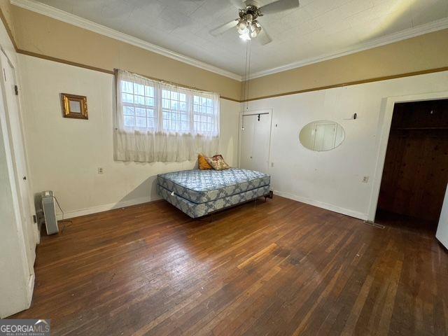 bedroom with ceiling fan, dark hardwood / wood-style floors, and ornamental molding