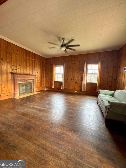 unfurnished living room with dark hardwood / wood-style floors, plenty of natural light, and wooden walls