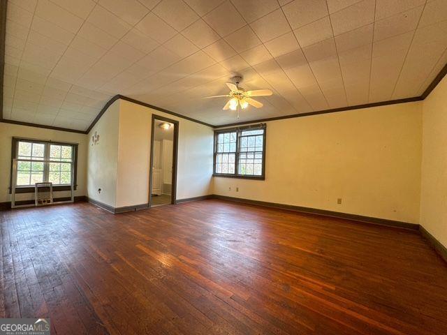 spare room featuring ceiling fan, dark wood-type flooring, and ornamental molding