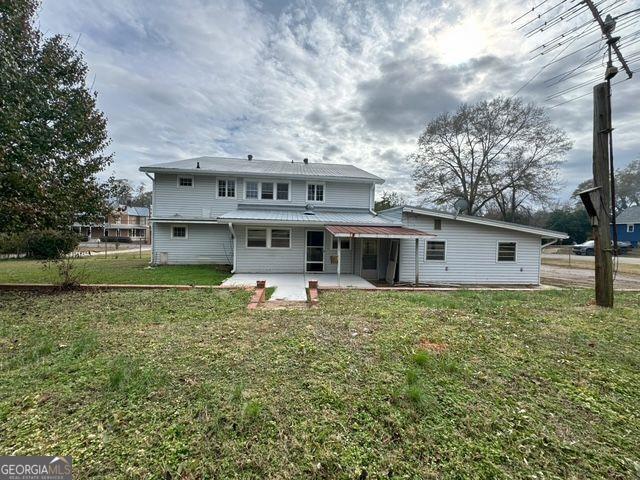 back of house featuring a lawn and a patio area