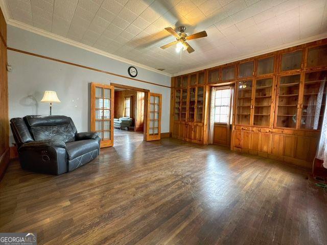 living room with french doors, crown molding, ceiling fan, and dark wood-type flooring