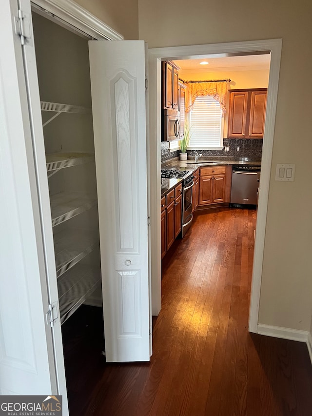 kitchen featuring appliances with stainless steel finishes, tasteful backsplash, sink, and dark hardwood / wood-style flooring