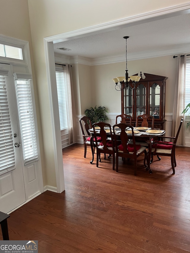 dining area with a notable chandelier, ornamental molding, plenty of natural light, and dark hardwood / wood-style flooring