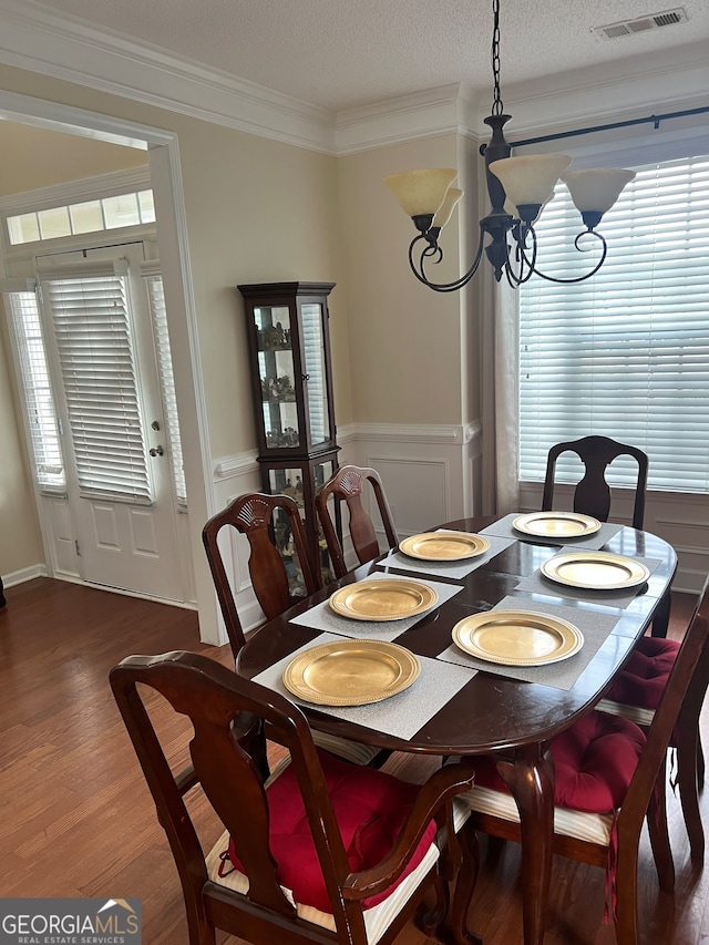 dining space featuring a textured ceiling, plenty of natural light, crown molding, an inviting chandelier, and dark hardwood / wood-style floors