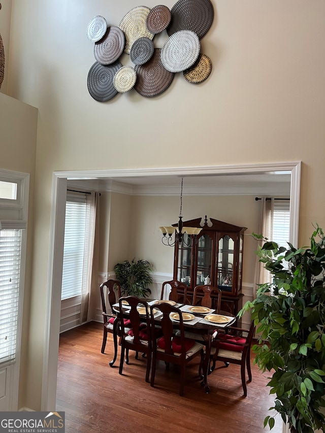 dining space featuring crown molding, hardwood / wood-style flooring, and an inviting chandelier