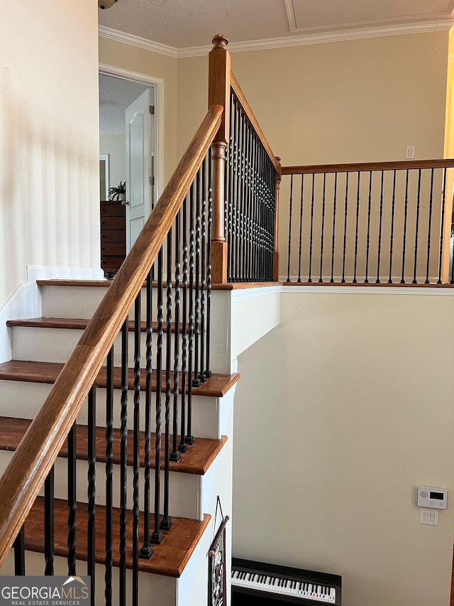 staircase featuring ornamental molding and a textured ceiling