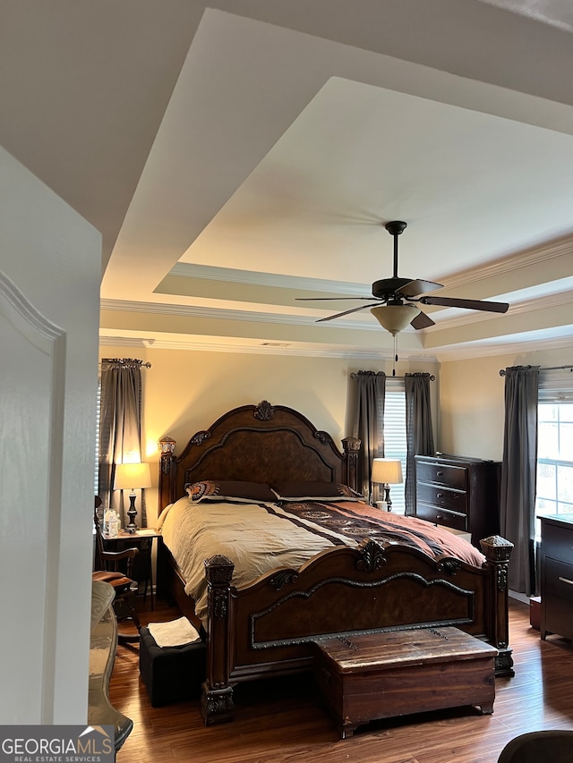 bedroom featuring ceiling fan, a raised ceiling, ornamental molding, and hardwood / wood-style floors