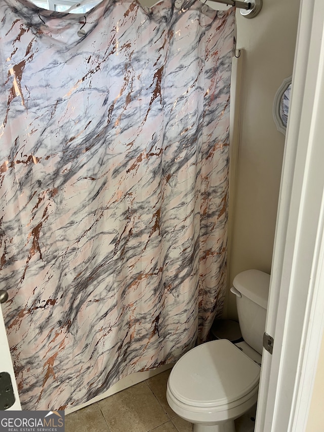 bathroom featuring toilet, tile patterned floors, and curtained shower