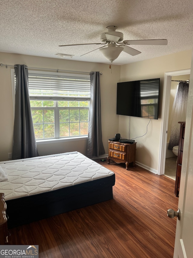 bedroom with a textured ceiling, wood-type flooring, and ceiling fan