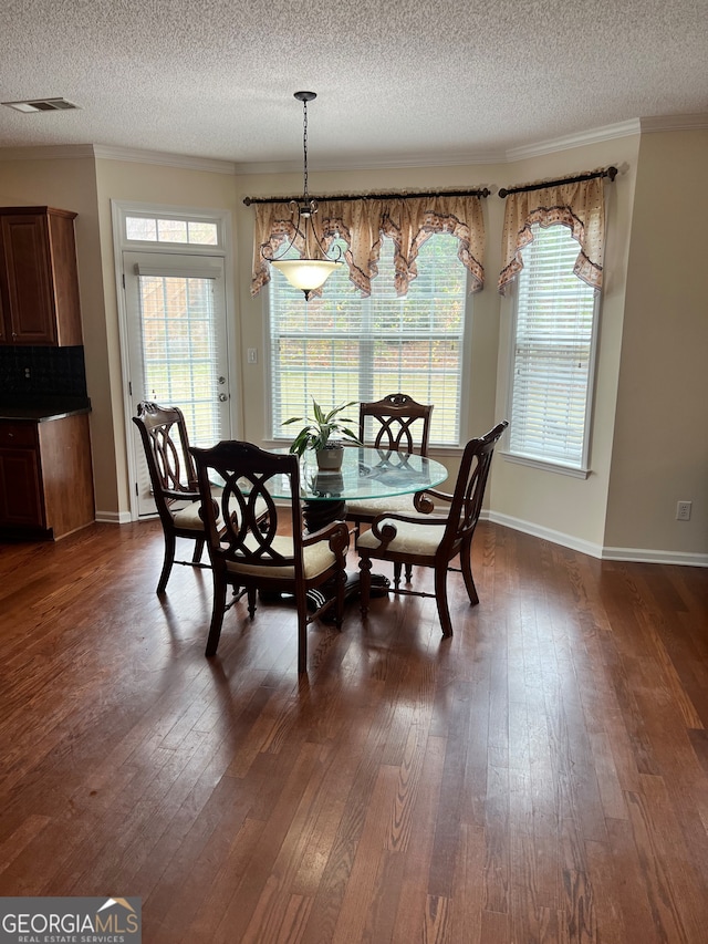 dining room featuring ornamental molding, a textured ceiling, and dark hardwood / wood-style flooring