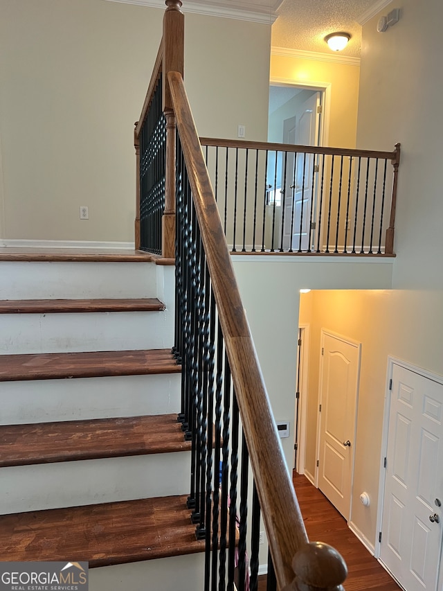 staircase featuring crown molding, hardwood / wood-style flooring, and a textured ceiling