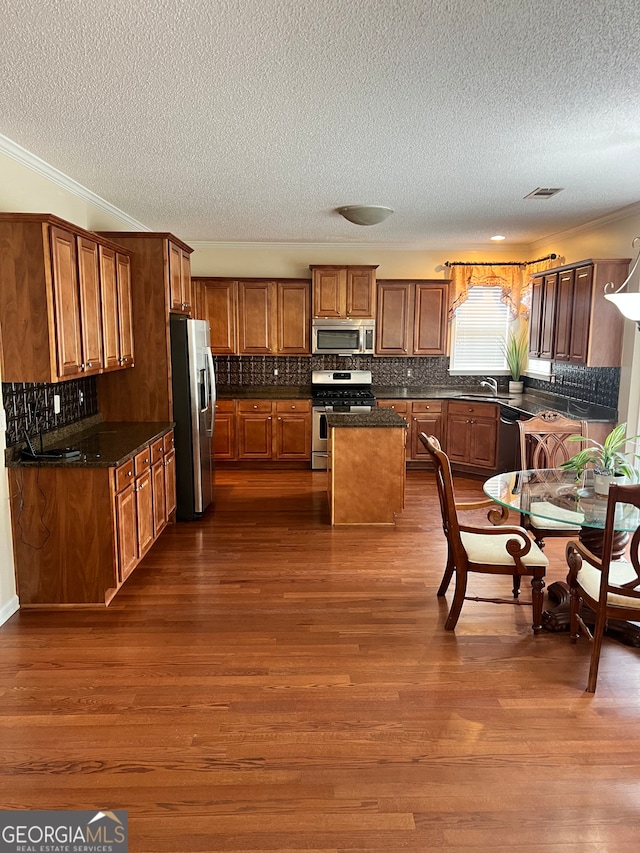 kitchen with stainless steel appliances, tasteful backsplash, a kitchen island, and dark hardwood / wood-style floors