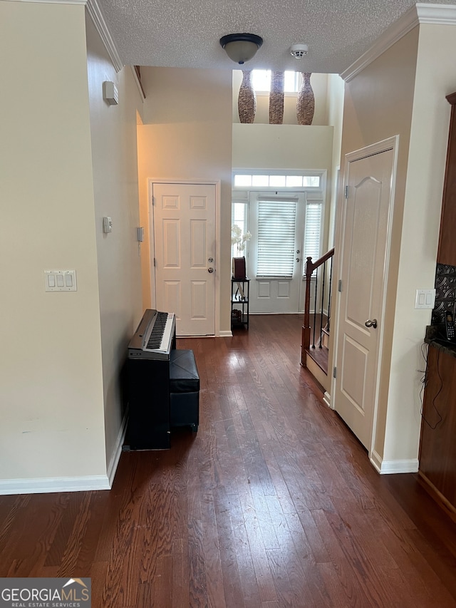 foyer entrance with ornamental molding, a textured ceiling, and dark hardwood / wood-style flooring