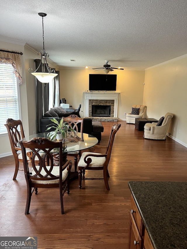 165 Summit Point Dr, Fayetteville, GA 30214 - dining space featuring a ceiling fan, a textured ceiling, crown molding, dark wood-style flooring, and a stone fireplace