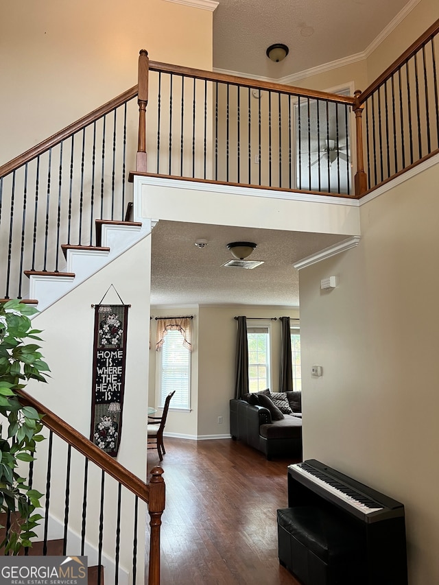 stairway featuring crown molding, a textured ceiling, and wood-type flooring