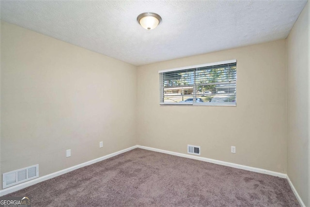 carpeted empty room featuring a textured ceiling