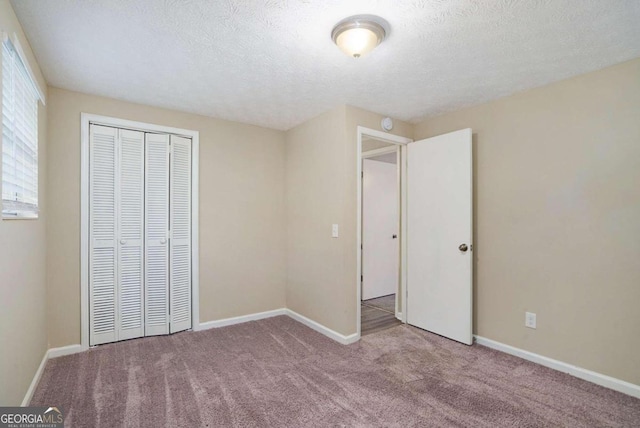 unfurnished bedroom with light carpet, a textured ceiling, and a closet