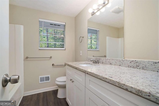 bathroom featuring hardwood / wood-style flooring, a tub to relax in, toilet, vanity, and a textured ceiling