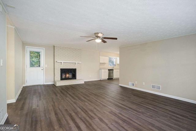 unfurnished living room with a textured ceiling, dark wood-type flooring, a fireplace, and ceiling fan