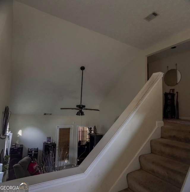 stairs featuring lofted ceiling and ceiling fan