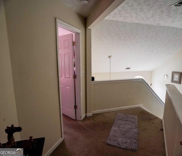 hall featuring a textured ceiling and carpet