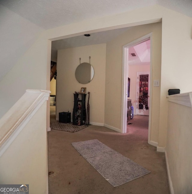 hallway with light carpet, a textured ceiling, and vaulted ceiling