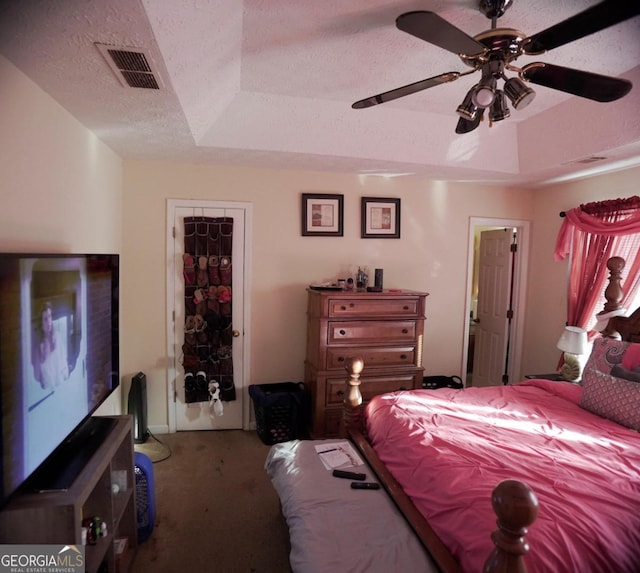 carpeted bedroom featuring a textured ceiling, a raised ceiling, and ceiling fan