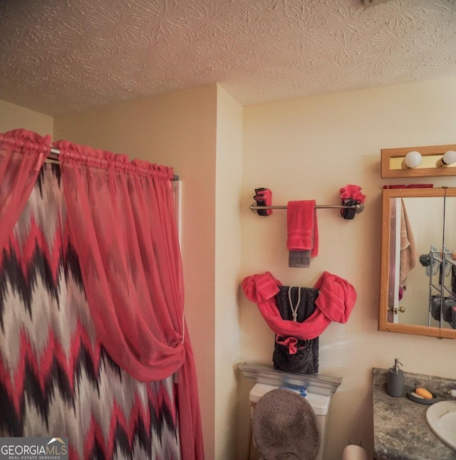 bathroom featuring toilet, a textured ceiling, and vanity