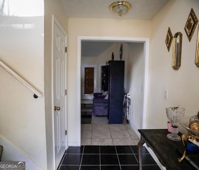 hallway featuring a textured ceiling and dark tile patterned floors