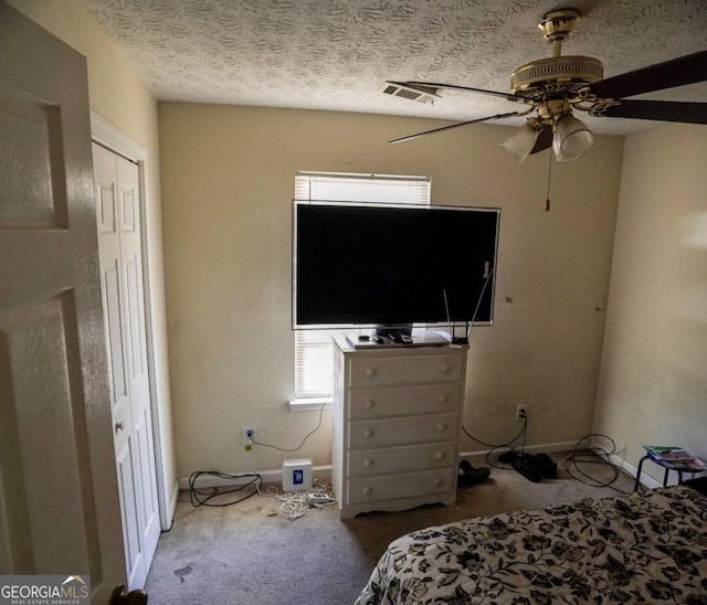 unfurnished bedroom featuring a closet, ceiling fan, a textured ceiling, and carpet floors