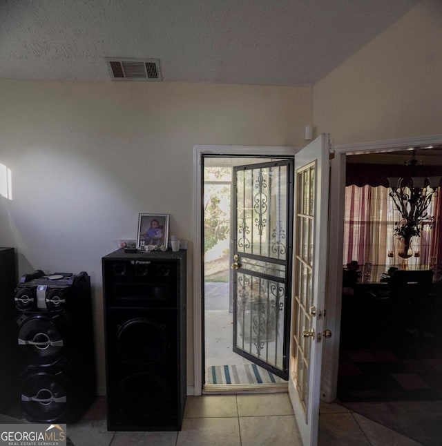 entryway with a textured ceiling and light tile patterned floors