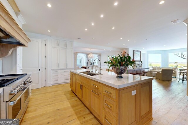 kitchen with decorative backsplash, sink, double oven range, light stone counters, and light hardwood / wood-style floors