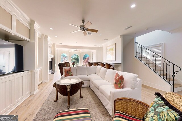 living room with crown molding, light wood-type flooring, and ceiling fan