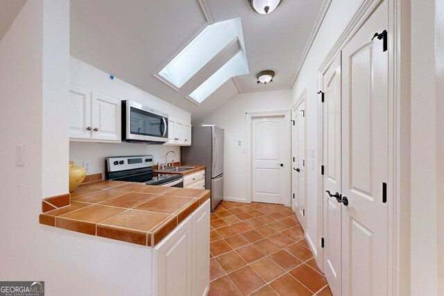 bathroom with toilet, vanity, tile patterned floors, and vaulted ceiling