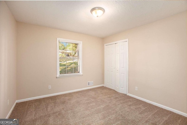 unfurnished bedroom featuring a closet, a textured ceiling, and carpet