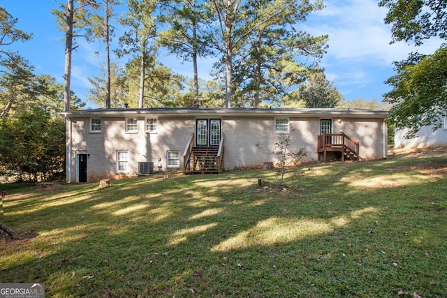 rear view of house with central AC and a lawn