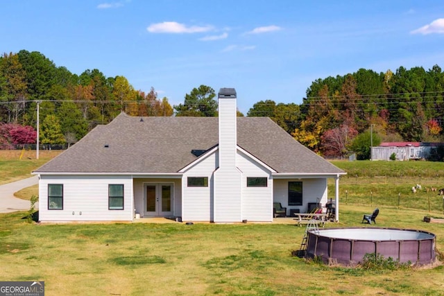 back of house with french doors, a fenced in pool, and a lawn