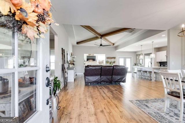 living room with beam ceiling, light wood-type flooring, and ceiling fan