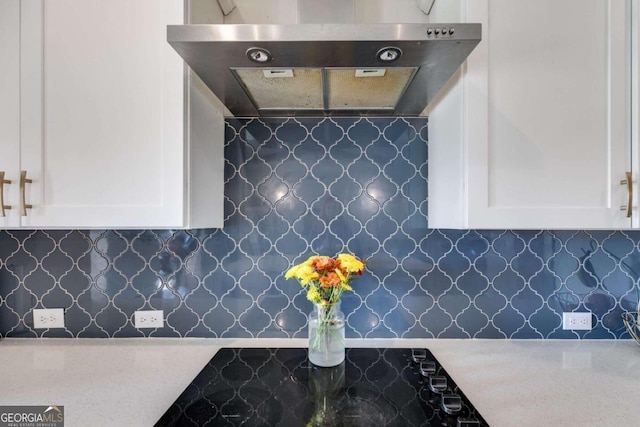 kitchen featuring white cabinets, range hood, and backsplash