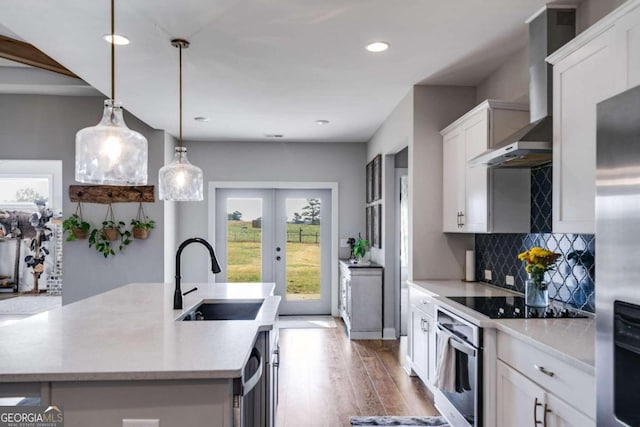 kitchen with appliances with stainless steel finishes, white cabinetry, hardwood / wood-style flooring, pendant lighting, and sink