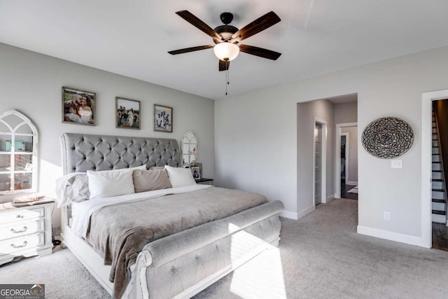 bedroom with ceiling fan, ensuite bath, and light colored carpet