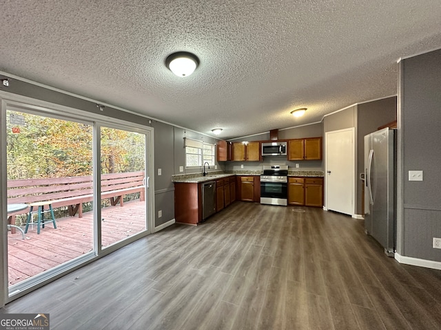 kitchen featuring lofted ceiling, dark wood-type flooring, stainless steel appliances, sink, and a textured ceiling