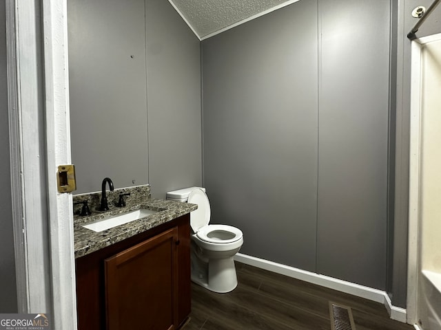 bathroom featuring vanity, a textured ceiling, hardwood / wood-style flooring, and toilet